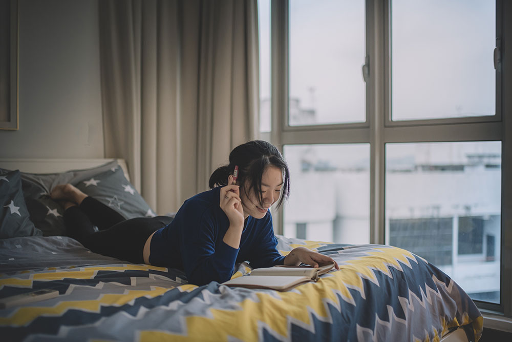 young woman relaxing on a bed reading