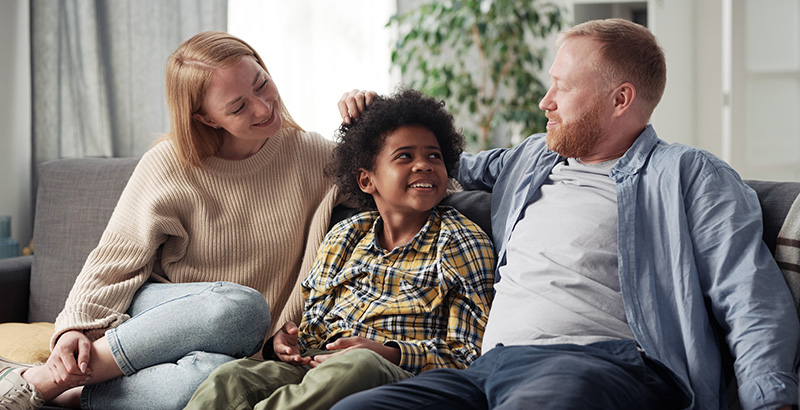 multicultural family sitting together on sofa