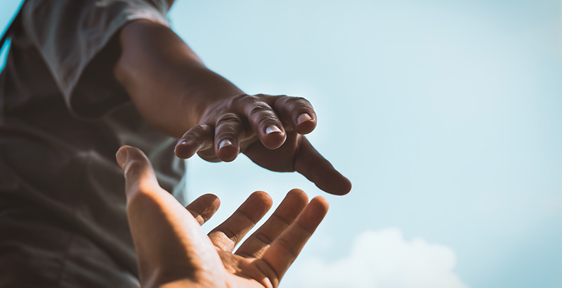 person reaching down to grab another person's hand