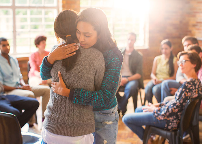 two women hugging in a group setting