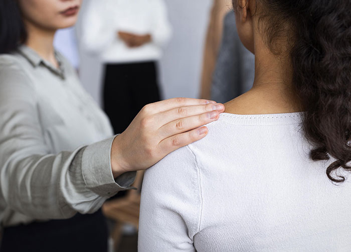 young woman placing hand on the shoulder of another woman