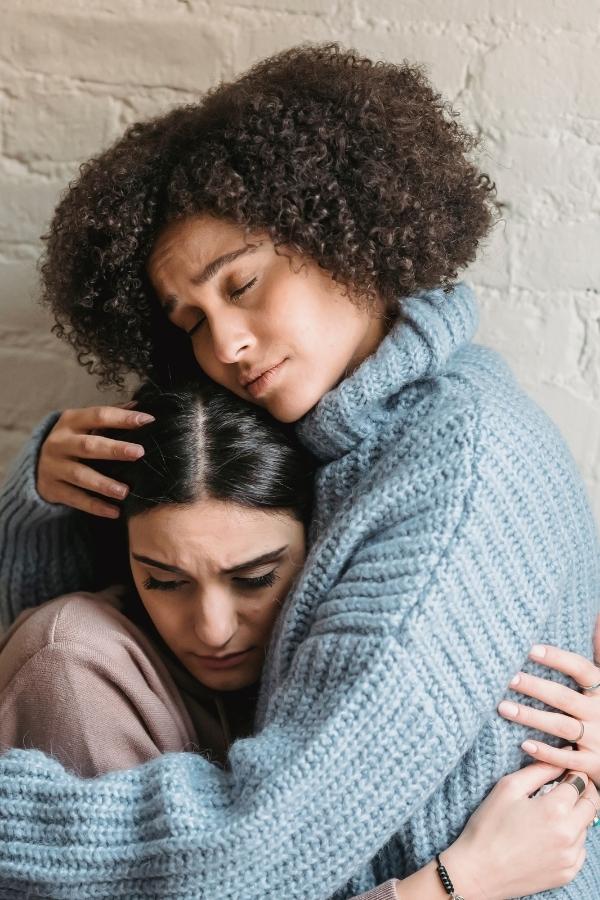 Balancing Between Caring For Yourself And Your Loved One. a woman supports and hugs another woman during a difficult time
