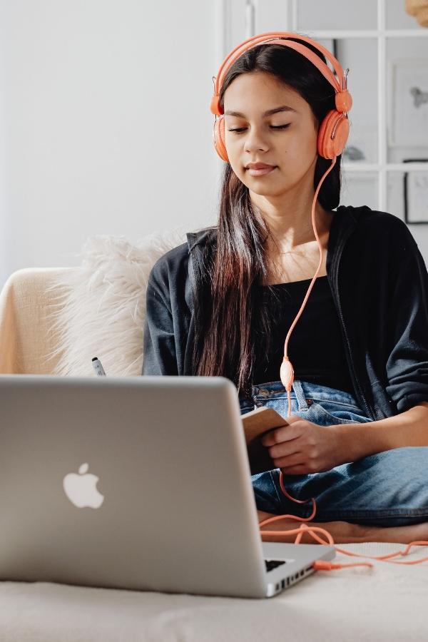 young woman wearing headphones and working at a laptop