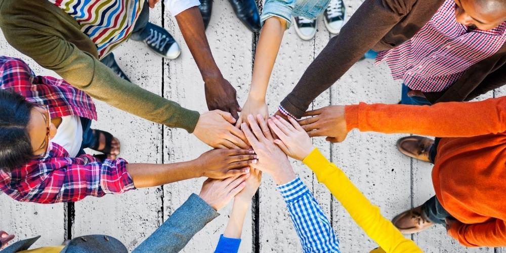 people in a circle with hands outstretched to center and touching