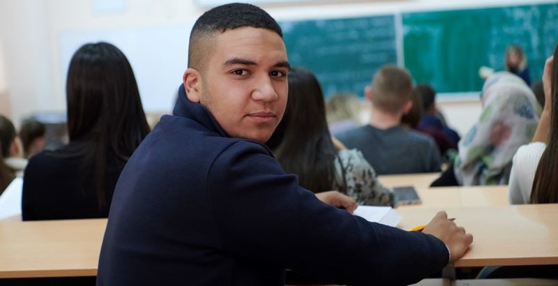 a young man in class facing toward the back of the class