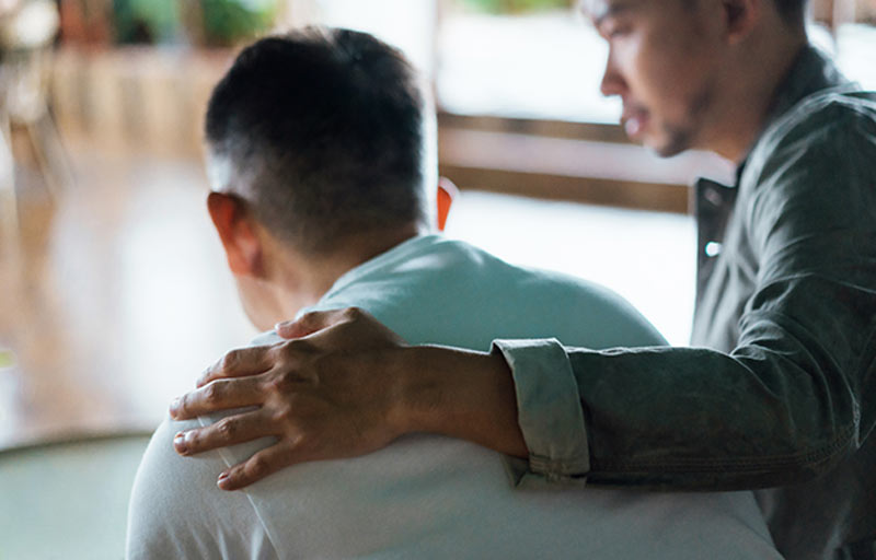 man with arm around another man for comfort